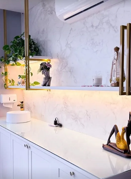 Sala de atendimento com bancada branca e prateleiras douradas
