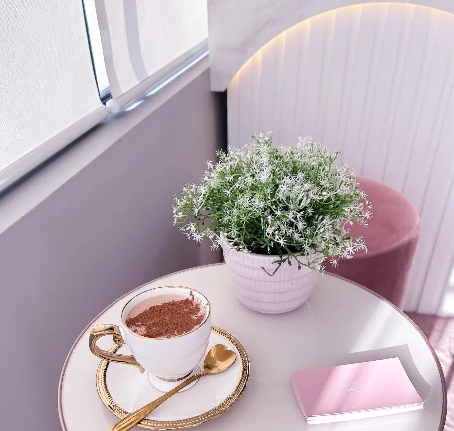 Cappuccino servido na recepção, ao lado de um vaso de flores