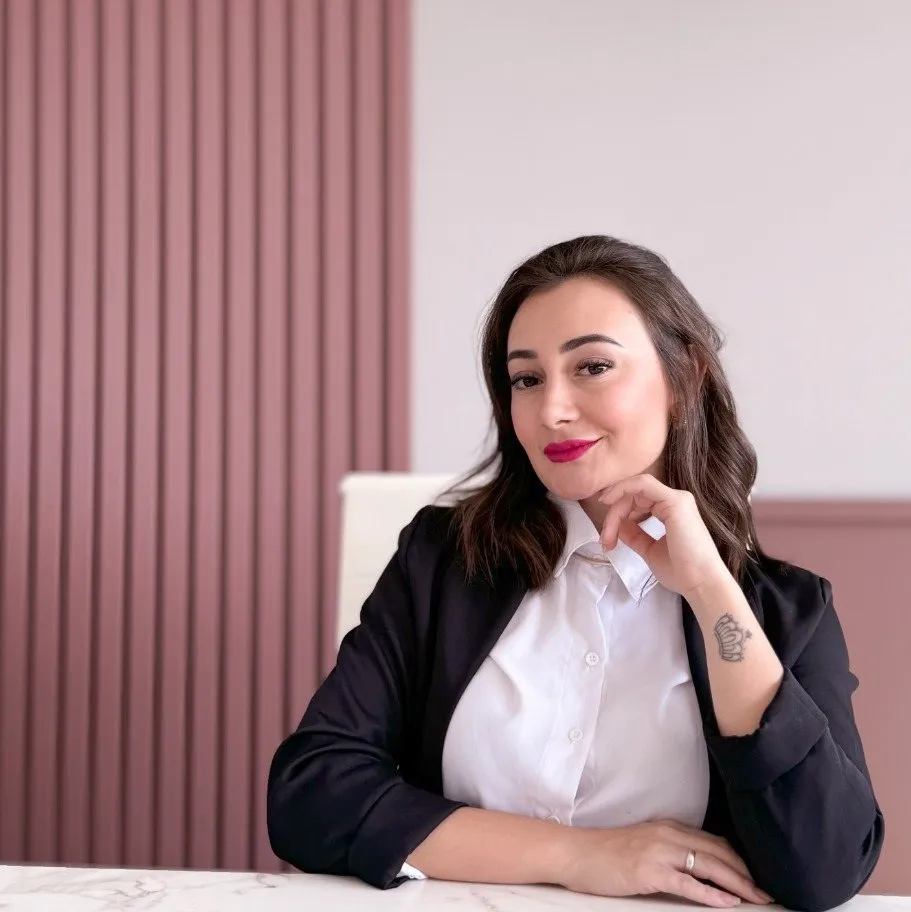 Karolin Ferrari sentada à mesa de avaliação, com o ripado rosé ao fundo